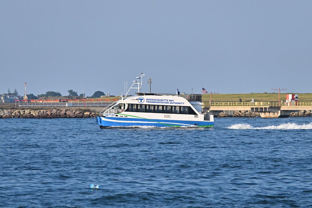 MBTA ferry Harbor Gem traveling across Boston Harbor, with airport approach equipment in the distance.