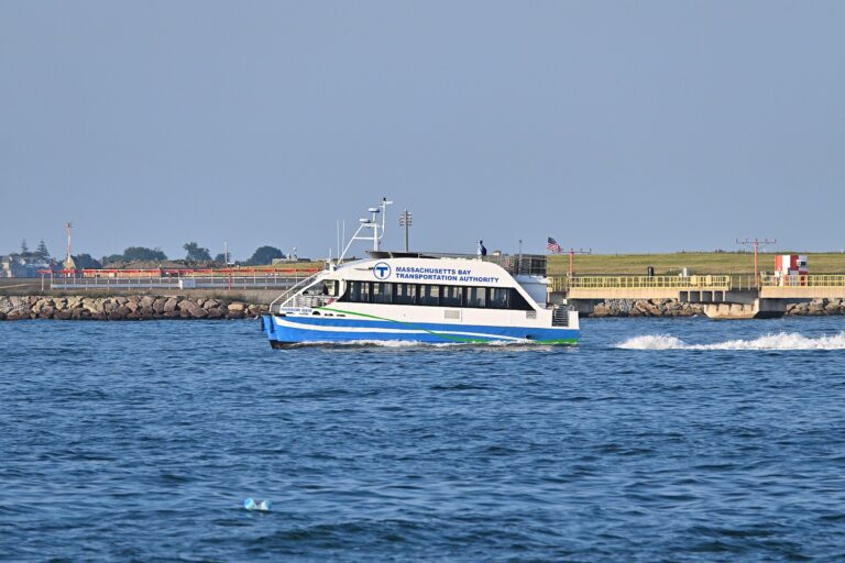 MBTA ferry Harbor Gem traveling across Boston Harbor, with airport approach equipment in the distance.